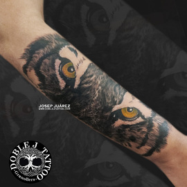 Tatuaje de tigre de ojos amarillos realista con sombras y texturas detalladas en el antebrazo, diseño personalizado por Doble J Tattoo.